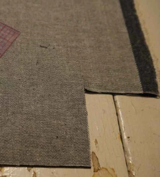 牛仔布布料,剪開一個角,形成一個側邊,用來製作一個用回收布料製成的DIY拉鍊手提袋。