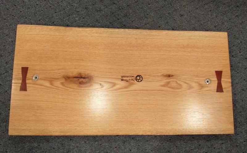 一塊成品木料，上面有兩個蝴蝶結形修補點，用來修復裂縫。