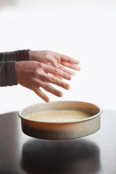 一個人將蛋糕糊從蛋糕模具中倒在堅硬的表面上,例如檯面上。