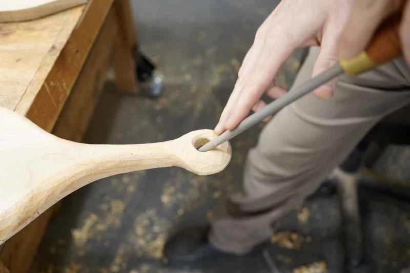 用圓銼刀或鼠尾銼刀將自製砧板手柄上的孔銼圓的人