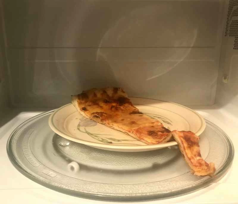 先把一片起司披薩放進微波爐加熱,再放進烤箱。這不是加熱披薩的最佳方法,但勉強夠用。