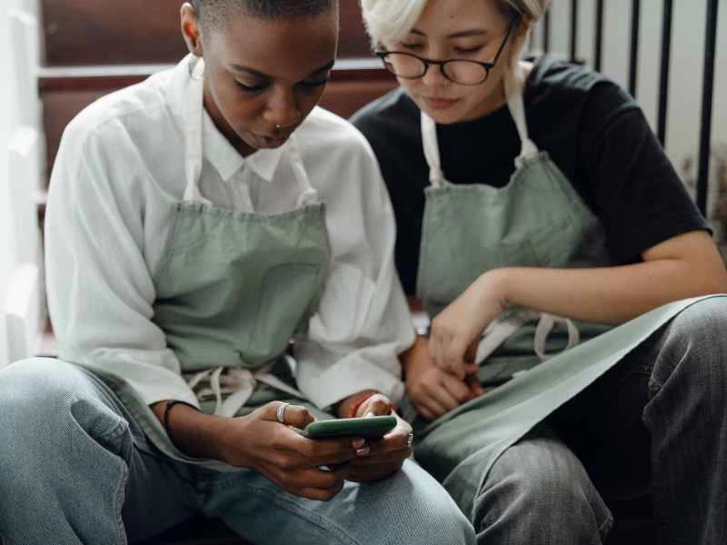 兩個人坐在樓梯上,用手機看影片。