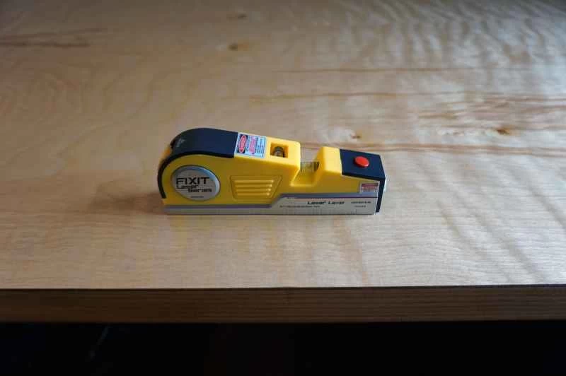 一個黃色的小水平儀正在檢查自製電腦桌的桌面是否水平。