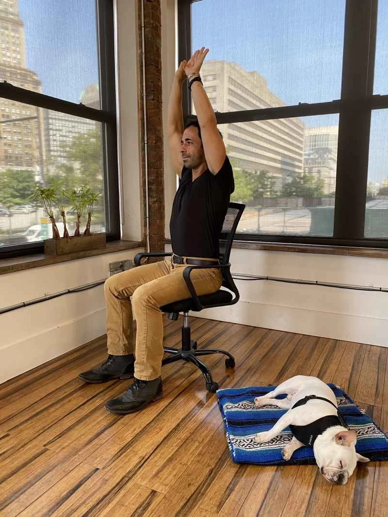 魯迪·格曼坐著時伸展雙臂過頭頂。