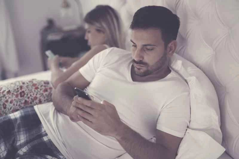 床上的情侶在看手機
