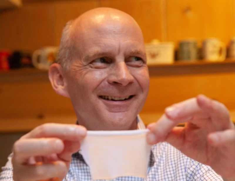 微笑的男子克里斯·伊萊，手裡拿著一塊白色布料。