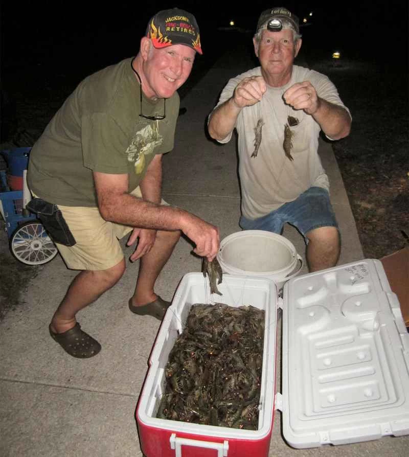 兩個男人圍著一箱蝦子。