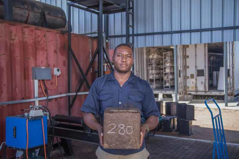 倉庫裡,一名身穿藍色襯衫的男子手持壓縮菌絲體。