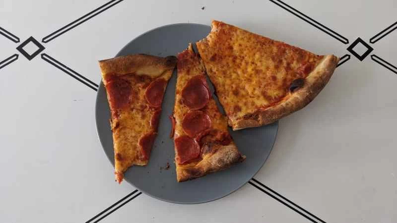 在關於如何重新加熱披薩的實驗中,三片披薩被微波爐加熱後放在藍色盤子上。