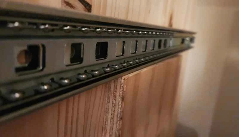 在抽屜滑軌下方墊一塊膠合板墊片，以便在安裝滑軌時將其固定到位。