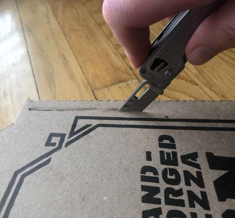 有人用刀子切割披薩盒，準備自製太陽能烤箱