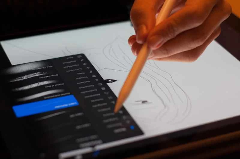 一隻手用觸控筆在 iPad 上進行繪畫,並使用 Adobe Photoshop 進行操作。
