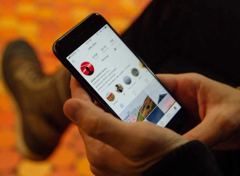 一手拿著手機,螢幕上顯示Instagram