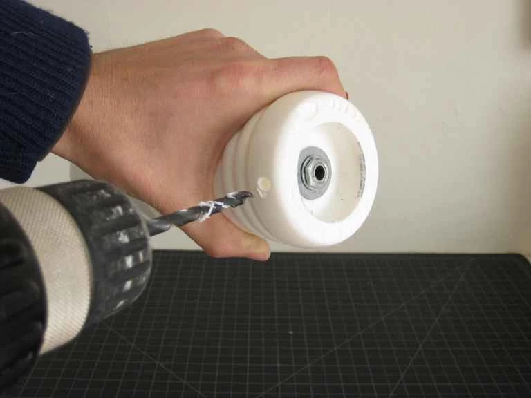 有人正在自製塑膠燈座底部鑽孔。