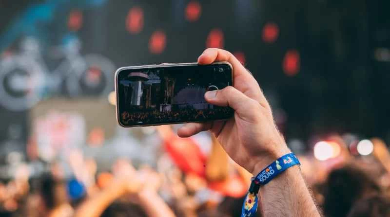 戶外音樂會上，一手舉著手機。