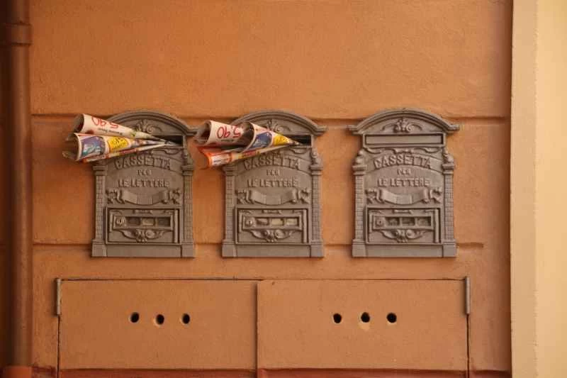 棕色的牆上嵌著三個舊郵箱。最左邊和中間的信箱都塞滿了郵件，都快溢出來了。