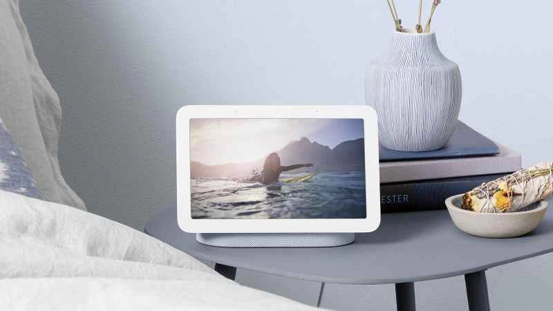 臥室床頭櫃上放著一台Google智慧音箱,螢幕上顯示著一位女性衝浪的圖片。