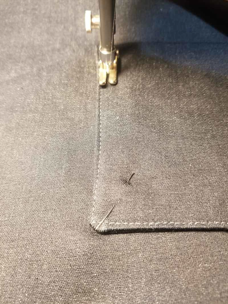 一台縫紉機正在用剩餘布料縫製一個自製拉鍊手提袋,袋子上正在縫製一個口袋。