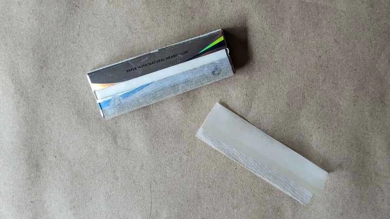 一包菸紙放在一張菸紙旁邊。