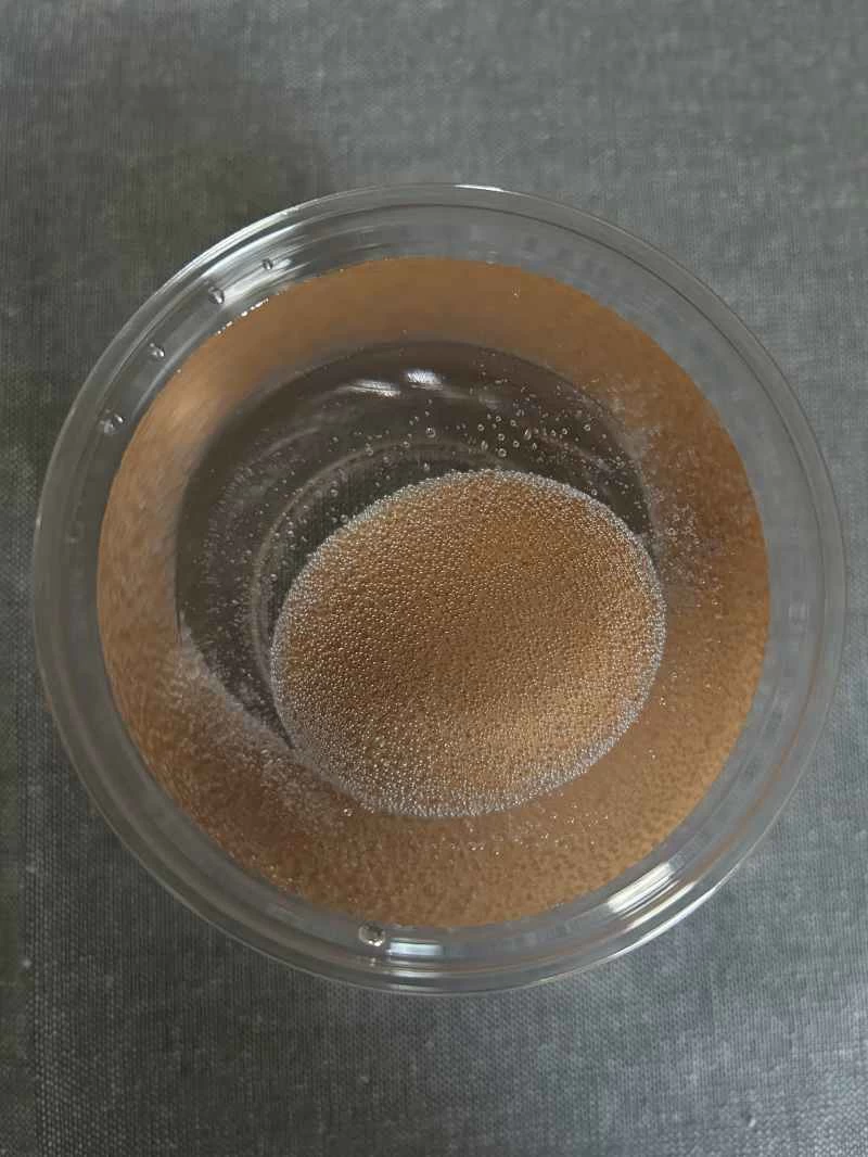 在一杯醋中,一顆棕色雞蛋周圍環繞著細小的氣泡。