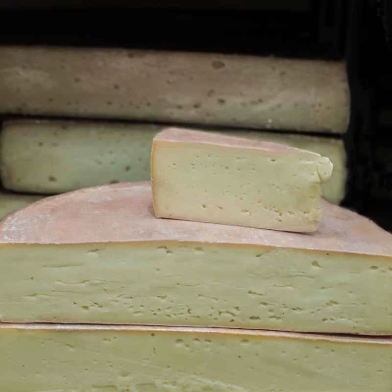 在起司展示櫃中，一塊軟起司楔子放在一個起司輪的兩半上面。