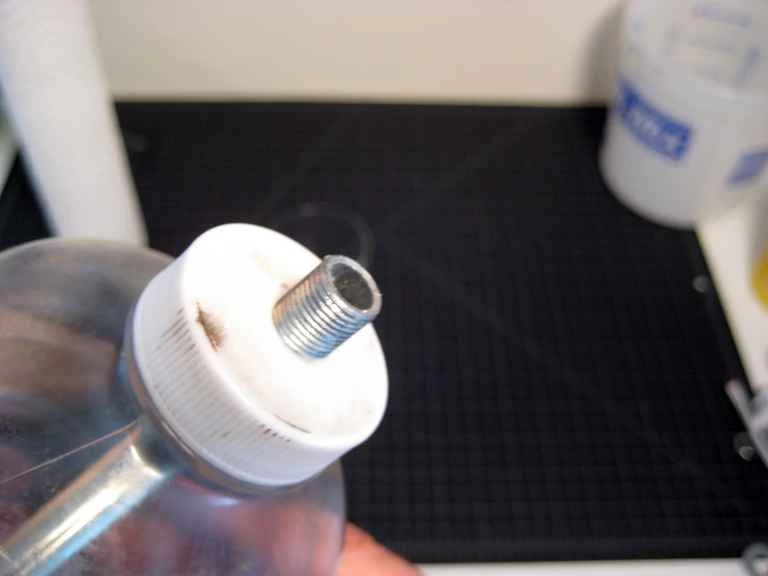 一個塑膠瓶蓋,裡面伸出一根螺紋的金屬桿。