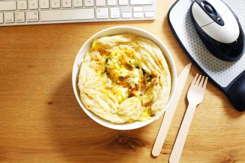 電腦旁的桌上放著一份布里起司西蘭花乳蛋餅。